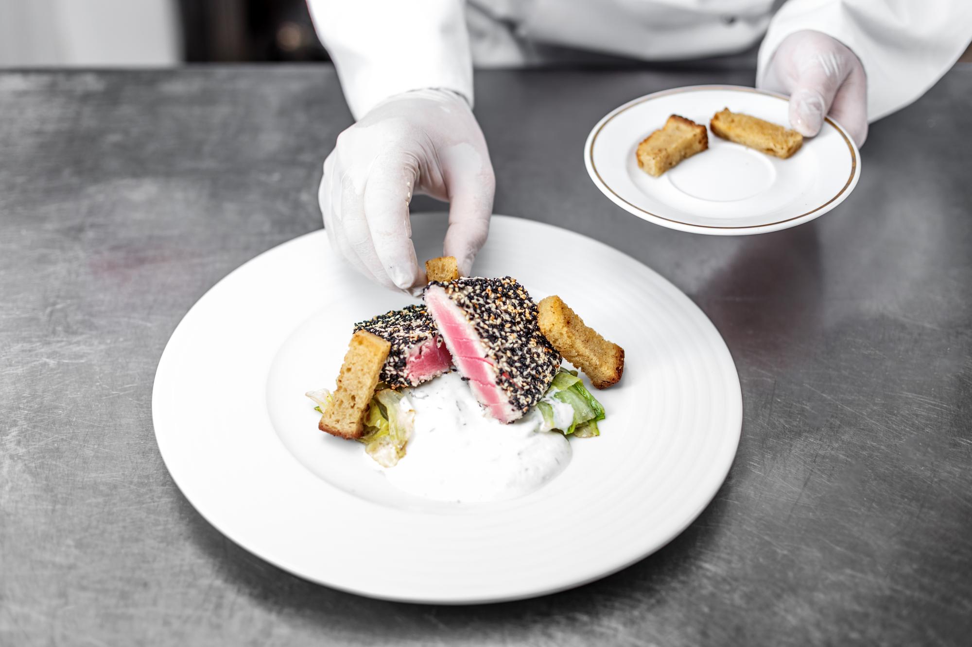Chef arranging plated dish in modern kitchen